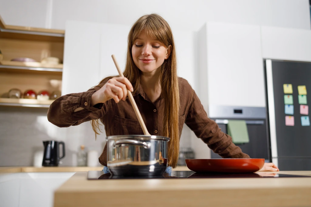 Sarah Jane Thompson, the author of Cookin' Corner, smiling as she stirs a pot of an American classic recipe in her kitchen.