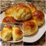A plate piled high with freshly baked, golden brown dinner rolls brushed with a shiny glaze, showing soft interior texture.