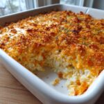 A scoop taken out of a baked Jalapeño popper dip showing creamy interior and crispy, golden-brown topping.