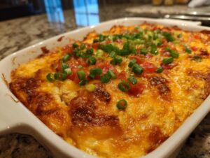 Close-up of a baked texas trash dip with melted orange cheese and green onions.