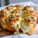 Close-up of cheesy Hawaiian roll garlic bread with melted cheese stretching as a piece is pulled away.