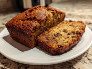 Close-up of a sliced chocolate chip mini banana bread loaf on a white plate.