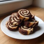 A stack of homemade chocolate and vanilla pinwheel cookies showing distinct dark brown and light yellow swirls.
