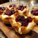 Close-up of baked cranberry brie bites in flaky puff pastry cups, ready to serve.