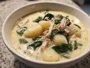 Close-up of a serving of creamy chicken gnocchi soup recipe with tender gnocchi, shredded chicken, and spinach.