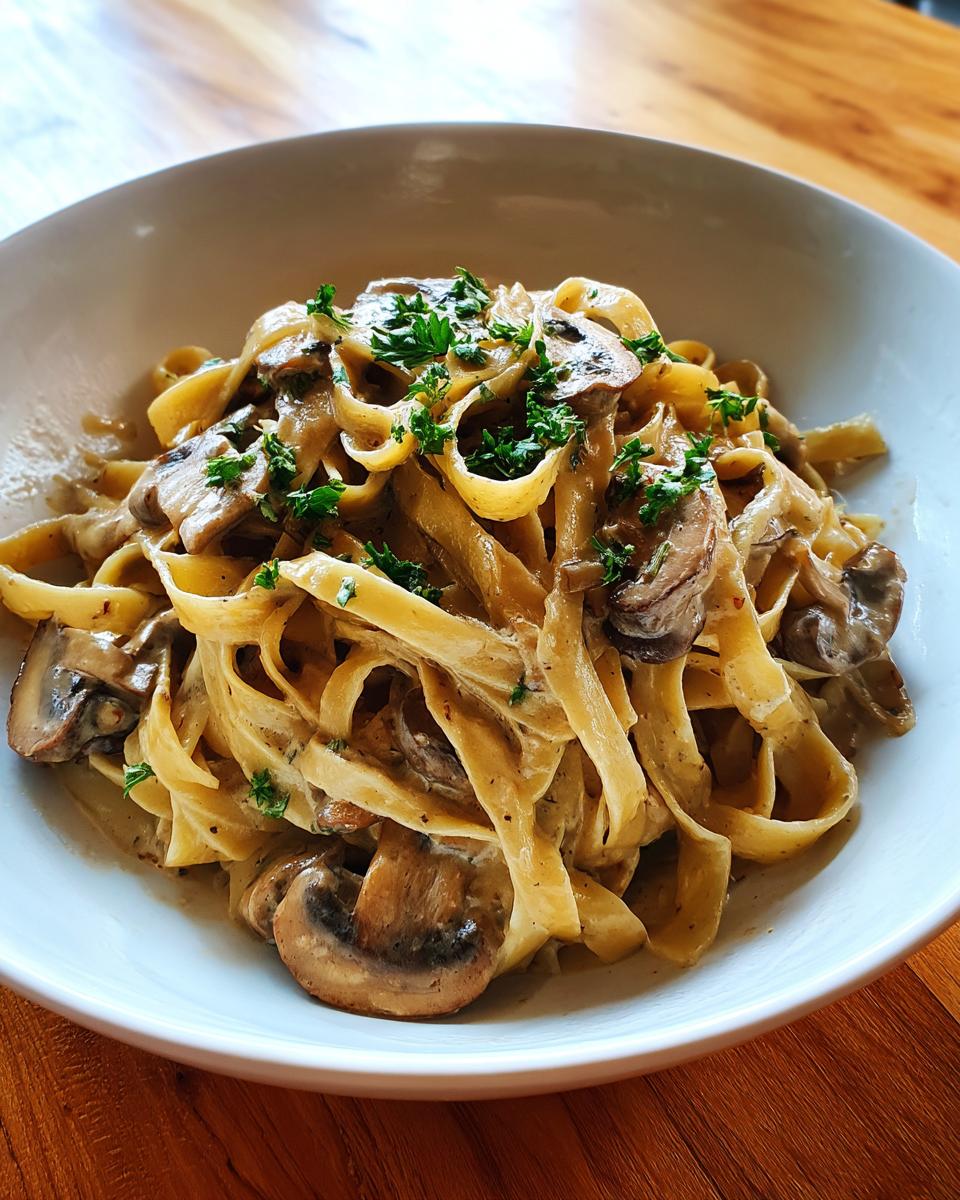 A close-up of creamy mushroom pasta made with fettuccine, topped with fresh parsley.