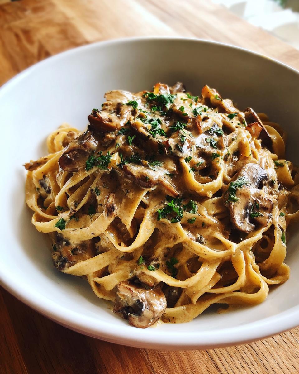 Close-up of creamy mushroom pasta made with fettuccine, rich sauce, and fresh parsley garnish.