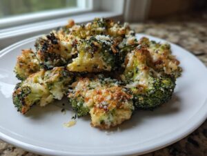 Close-up of crispy, oven-roasted smashed broccoli florets topped with melted and browned Parmesan cheese.
