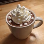 A white mug filled with rich crockpot hot chocolate recipe topped with whipped cream and mini marshmallows.