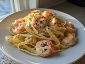 A close-up of creamy garlic butter shrimp pasta, featuring large shrimp over fettuccine noodles, garnished with parsley.