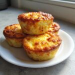 Four golden-brown cottage cheese egg cups stacked on a white plate, perfect for a Starbucks hack.