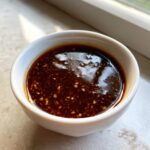 Close-up of rich, dark homemade teriyaki sauce with visible flecks of garlic or ginger.