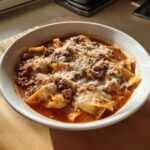 Close-up of a white bowl filled with rich Instant Pot Lasagna Soup, topped with melted mozzarella and grated Parmesan cheese.