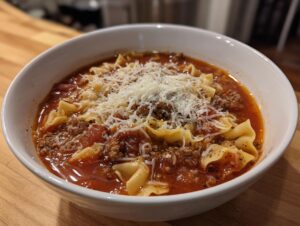 Close-up of a white bowl filled with rich Instant Pot Lasagna Soup, topped generously with shredded Parmesan cheese.