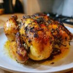 A perfectly cooked, juicy roasted chicken with golden, crispy skin seasoned with herbs.