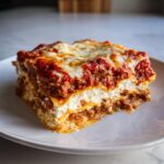 A thick, layered slice of Lasagna with Cottage Cheese, meat sauce, and melted mozzarella on top.