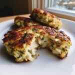 Close-up of a golden-brown Maryland crab cake broken open to show the flaky white crab meat inside.