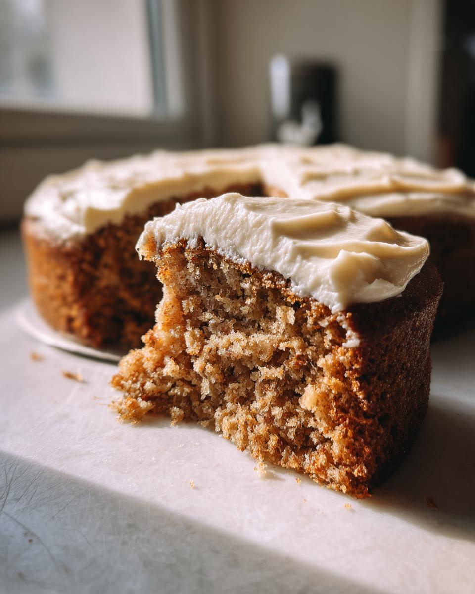 Close-up of a moist slice of apple spice cake showing the crumb texture, topped with thick cream cheese frosting.