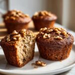 Close-up of two delicious banana nut muffins, one cut in half showing the moist interior and walnuts.