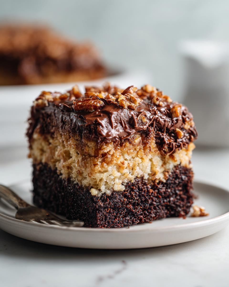 Close-up of a moist slice of german chocolate poke cake showing chocolate cake base, coconut layer, and pecan topping.