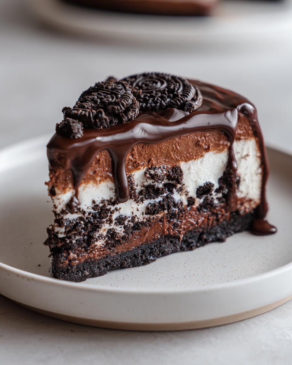 A decadent slice of no-bake chocolate cheesecake featuring layers of dark crust, white filling, and chocolate mousse, topped with ganache and cookies.