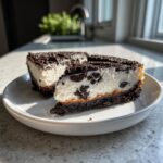 Two slices of rich oreo cheesecake bites showing a creamy white filling studded with dark chocolate cookie pieces.