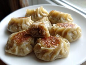 Close-up of pan-fried Traditional Chinese Dumplings, showing a golden-brown sear and one dumpling cut open to reveal the savory filling.