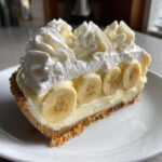 A delicious slice of banana cream pie recipe featuring a graham cracker crust, creamy filling, banana slices, and whipped cream.