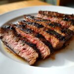 Close-up of medium-rare steak slices showing char marks and juices, prepared with carne asada marinade.