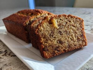 Close-up of a freshly baked sugar free banana bread loaf with two slices cut, showing moist texture and chocolate chips.