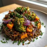 A beautifully plated veggie lentil salad featuring lentils topped with roasted broccoli, sweet potato cubes, and red onion, garnished with parsley.