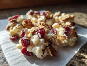 Close-up of several delicious white chocolate cranberry pecan clusters resting on parchment paper.
