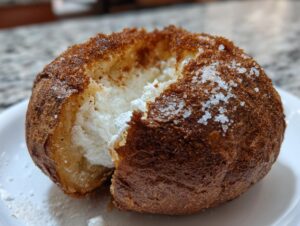 Close-up of a perfectly cooked air fryer baked potato with a dark, crispy skin topped with coarse salt crystals and fluffy white interior.
