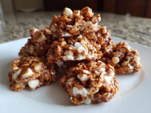 A close-up stack of rich, brown avalanche cookies mixed with white chocolate chips on a white plate.