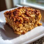 A close-up, sunlit square of amazing baked oatmeal with a crispy, caramelized top layer.