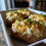 Close-up of twice-baked potato casserole halves topped with melted cheddar and green onions.