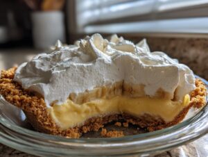Close-up of a slice removed from a banana cream pie showing layers of graham cracker crust, custard, banana slices, and thick whipped cream.
