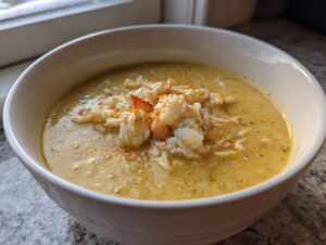 A close-up of a creamy, rich bowl of crab soup topped with generous flakes of white crab meat and a sprinkle of paprika.