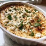 Close-up of hot, baked street corn dip topped with crumbled white cheese and fresh cilantro.