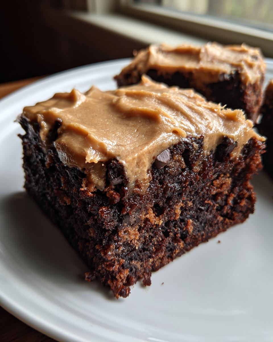 Close-up of a rich, dark chocolate banana bread brownies square topped with creamy peanut butter frosting.