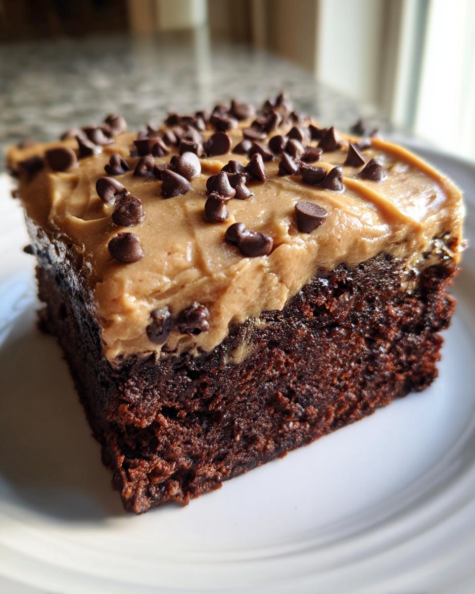 A thick square slice of rich chocolate banana bread brownies topped with peanut butter frosting and mini chocolate chips.