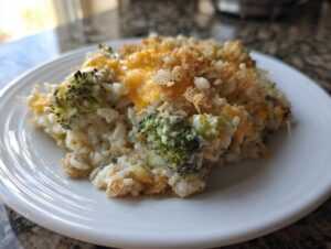 A close-up serving of creamy broccoli rice casserole topped with melted cheddar cheese and crispy breadcrumbs.