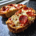 Close-up of two halves of cheesy pepperoni pizza bagels, melted cheese dripping over toasted bread.