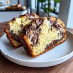 Two thick slices of baked chocolate chip cheesecake cookies showing a rich, marbled interior.