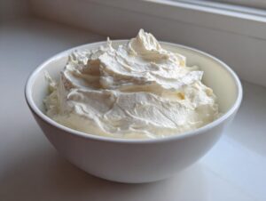 A close-up of thick, whipped cream cheese fruit dip mounded high in a small white bowl.