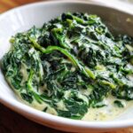A close-up shot of rich, vibrant green spinach coated in a creamy white sauce, showcasing the amazing creamed spinach recipe.