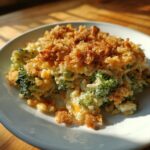 A close-up serving of creamy broccoli rice casserole topped with a golden, crunchy breadcrumb topping.