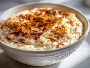Close-up of a bowl of creamy rice pudding generously dusted with ground cinnamon.