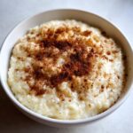 Close-up of a bowl of creamy rice pudding generously sprinkled with ground cinnamon.