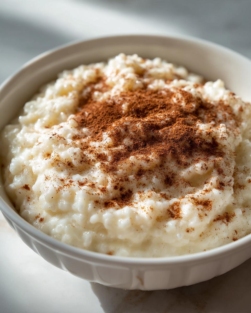 Close-up of a bowl of creamy rice pudding generously topped with ground cinnamon.